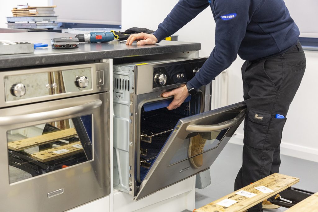 Domex engineer pulling oven out from under the counter