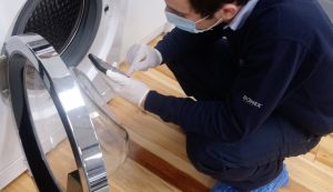 Domex engineer repairing washing machine in COVID-19 safety PPE
