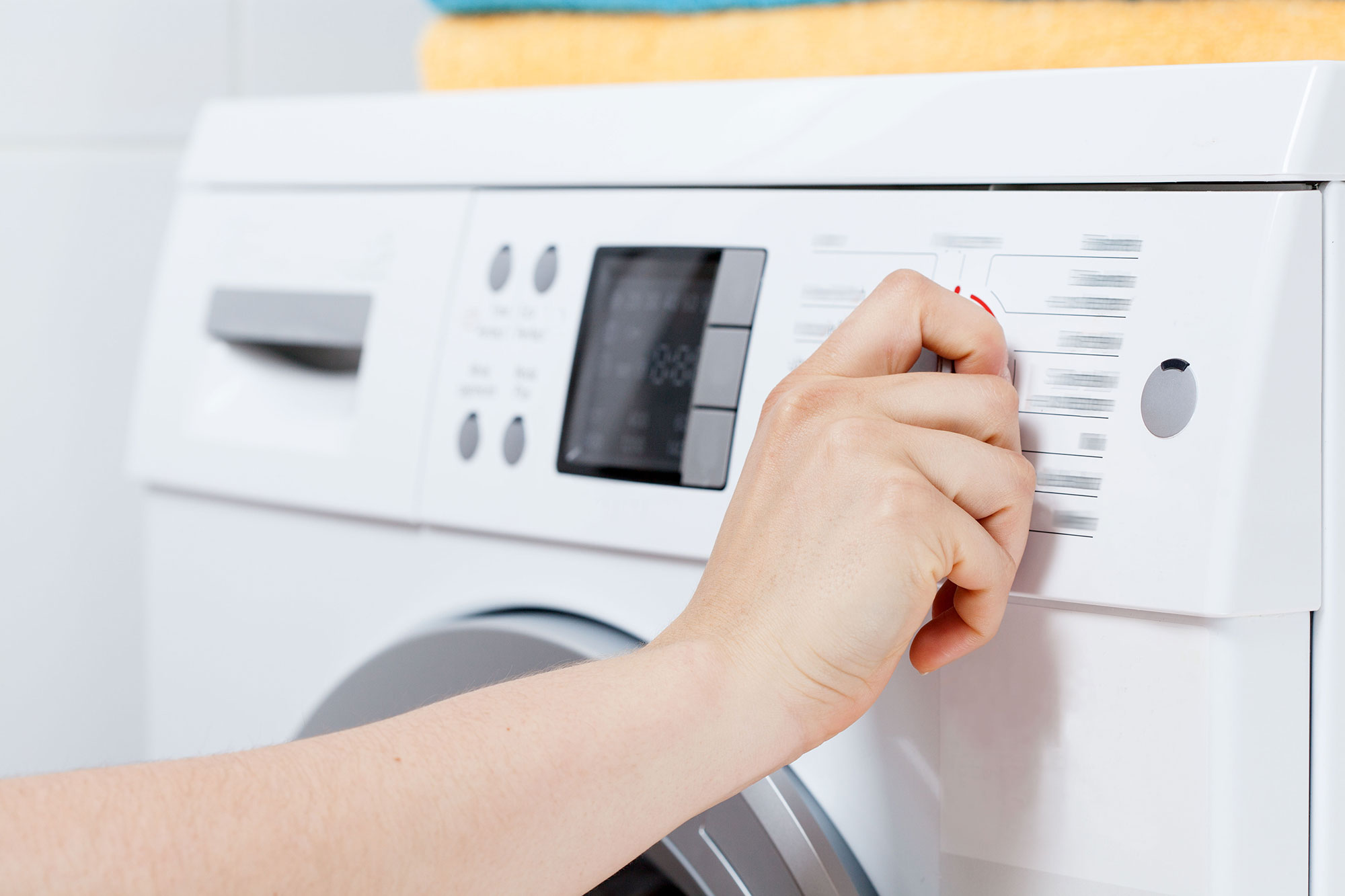 Woman turning dial on washing machine